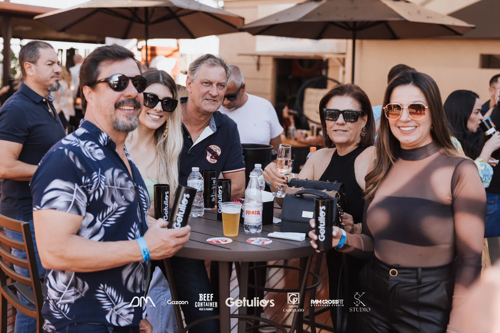Convidados em evento corporativo com as logos dos patrocinadores estampadas na foto